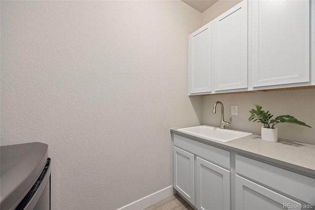 washroom featuring baseboards and a sink