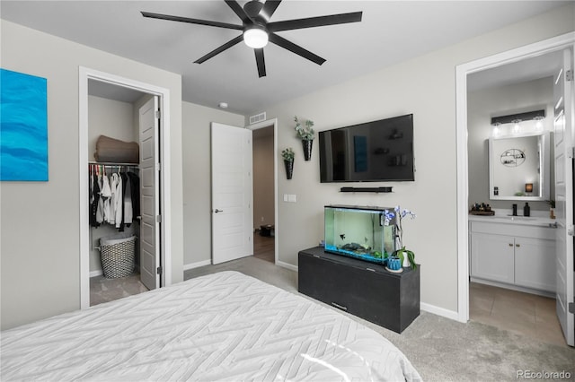 bedroom with light carpet, baseboards, a closet, a walk in closet, and ensuite bath