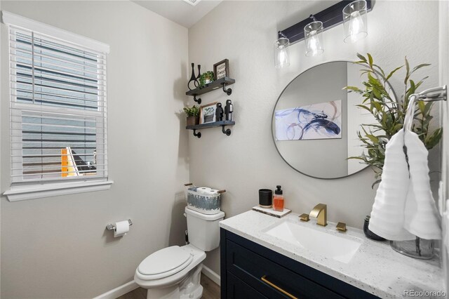 bathroom featuring toilet, baseboards, and vanity