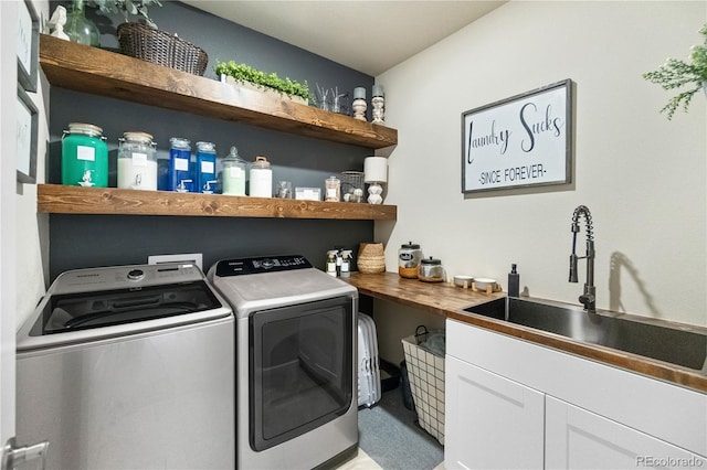 washroom featuring cabinet space, a sink, and washer and clothes dryer