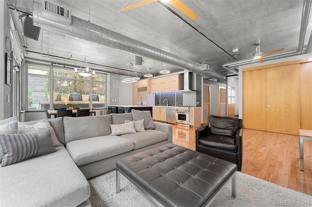 living room featuring sink, ceiling fan, and hardwood / wood-style flooring