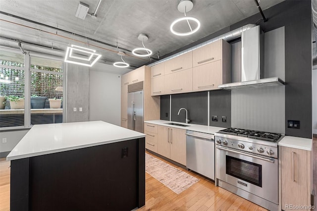 kitchen featuring wall chimney exhaust hood, high quality appliances, decorative light fixtures, a kitchen island, and sink