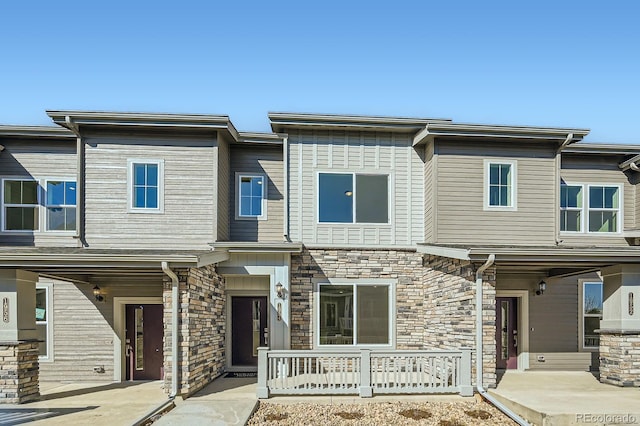 townhome / multi-family property with covered porch and stone siding