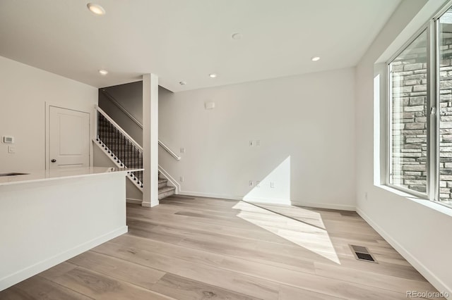 unfurnished room with visible vents, recessed lighting, stairway, and light wood-style floors