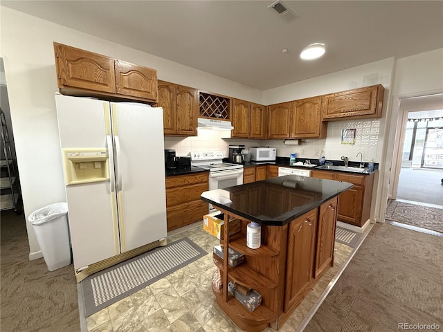 183 E Ave, Limon, CO 80828 - kitchen with white appliances, under cabinet range hood, dark countertops, a sink, and brown cabinets
