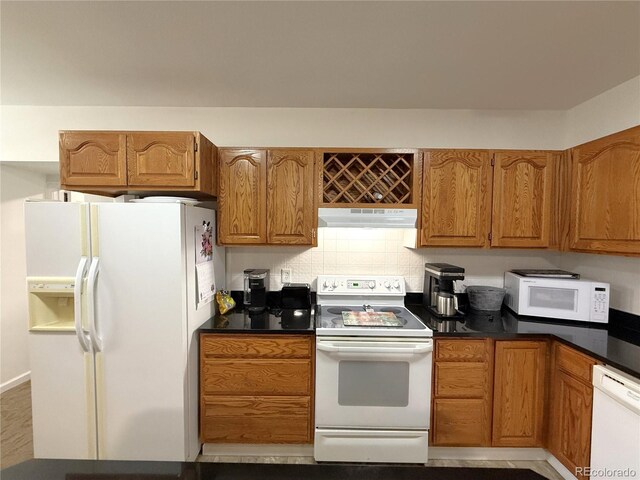 183 E Ave, Limon, CO 80828 - kitchen featuring white appliances, under cabinet range hood, dark countertops, and brown cabinets