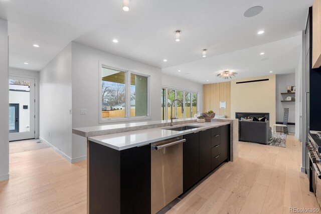 kitchen featuring a sink, dishwasher, dark cabinets, light wood finished floors, and recessed lighting