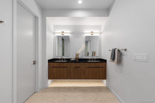 full bath with double vanity and baseboards