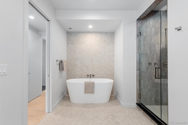 bathroom with a shower stall, a freestanding tub, recessed lighting, and baseboards