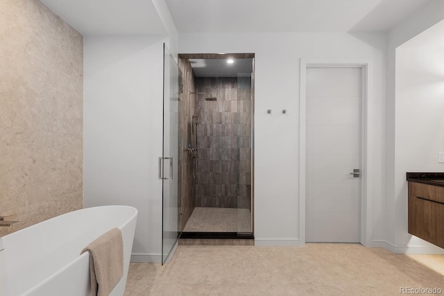 full bathroom with a stall shower, a soaking tub, baseboards, vanity, and tile walls