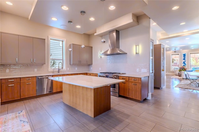 kitchen featuring wall chimney range hood, decorative backsplash, appliances with stainless steel finishes, and a sink