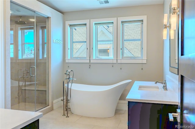 bathroom with a stall shower, vanity, a freestanding bath, and tile patterned flooring