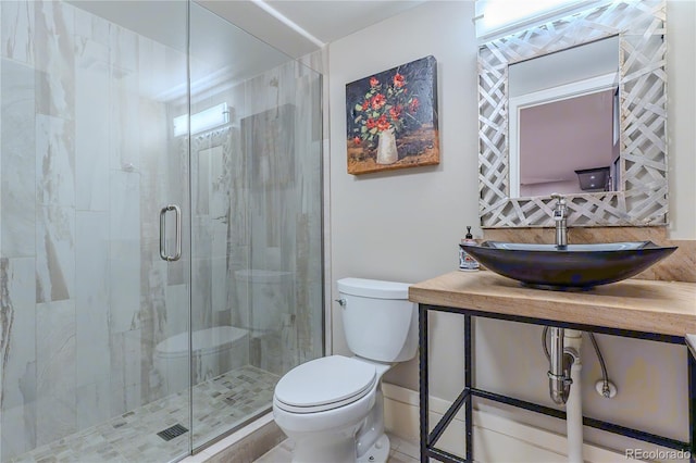 bathroom with a sink, toilet, and a shower stall