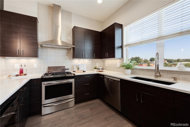 7861 W 51st Ave Unit B, Arvada, CO 80002 - kitchen featuring appliances with stainless steel finishes, wall chimney range hood, decorative backsplash, light countertops, and wood finished floors