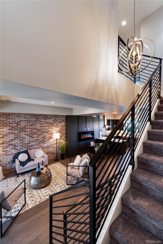 7861 W 51st Ave Unit B, Arvada, CO 80002 - staircase with wood finished floors, brick wall, a high ceiling, a chandelier, and recessed lighting