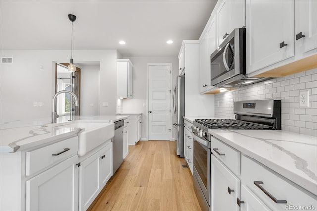 8028 Williams Fork Ave, Littleton, CO 80125 - kitchen with appliances with stainless steel finishes, white cabinets, light wood finished floors, recessed lighting, and light stone counters