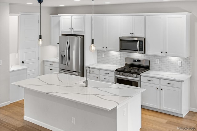 8028 Williams Fork Ave, Littleton, CO 80125 - kitchen featuring stainless steel appliances, white cabinetry, light wood-style floors, decorative backsplash, and recessed lighting