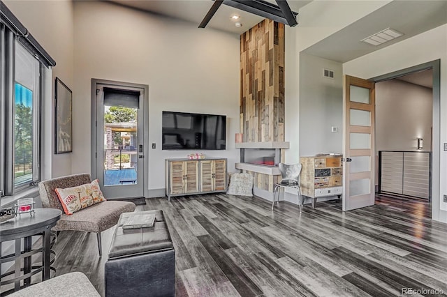 living room featuring a towering ceiling, visible vents, and wood finished floors