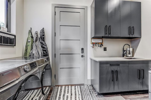 laundry area featuring dark wood-style floors, washing machine and clothes dryer, a sink, and cabinet space