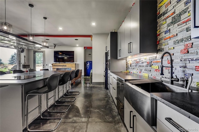 kitchen with dark countertops, open floor plan, hanging light fixtures, and a kitchen bar