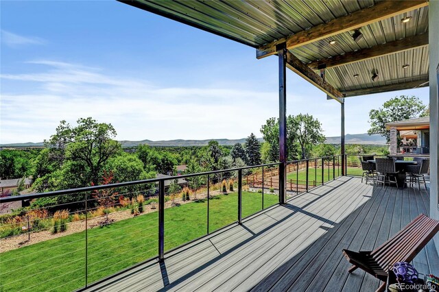 wooden terrace with outdoor dining area and a lawn