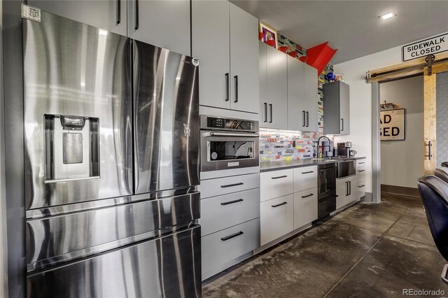 kitchen with appliances with stainless steel finishes, a barn door, modern cabinets, and decorative backsplash