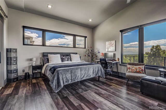 bedroom with dark wood-style floors, a barn door, multiple windows, and vaulted ceiling