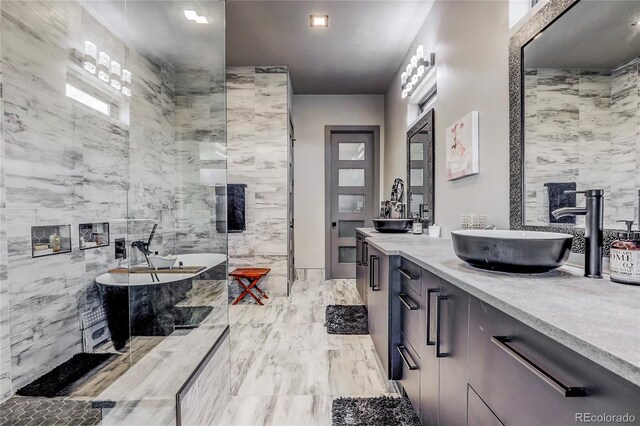 bathroom featuring a sink, tile walls, a freestanding bath, marble finish floor, and double vanity