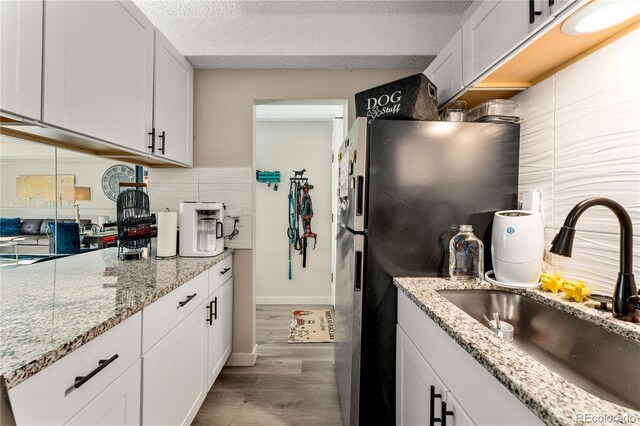 1265 Race St Unit 203, Denver, CO 80206 - kitchen featuring a sink, wood finished floors, white cabinets, a textured ceiling, and freestanding refrigerator