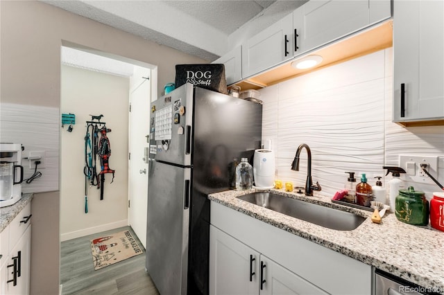 1265 Race St Unit 203, Denver, CO 80206 - kitchen with stainless steel appliances, a sink, tasteful backsplash, light wood-type flooring, and white cabinets