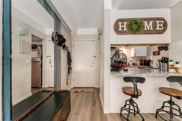 1265 Race St Unit 203, Denver, CO 80206 - interior space with light wood finished floors, a breakfast bar, a textured ceiling, baseboards, and freestanding refrigerator