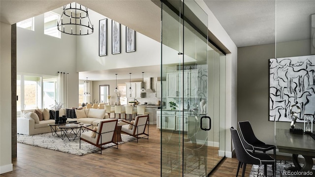 interior space featuring a chandelier, wood-type flooring, a textured ceiling, and a high ceiling