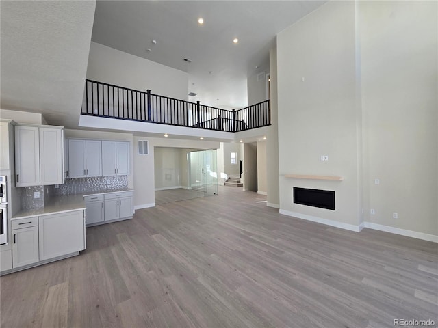 unfurnished living room featuring a towering ceiling and light wood-type flooring