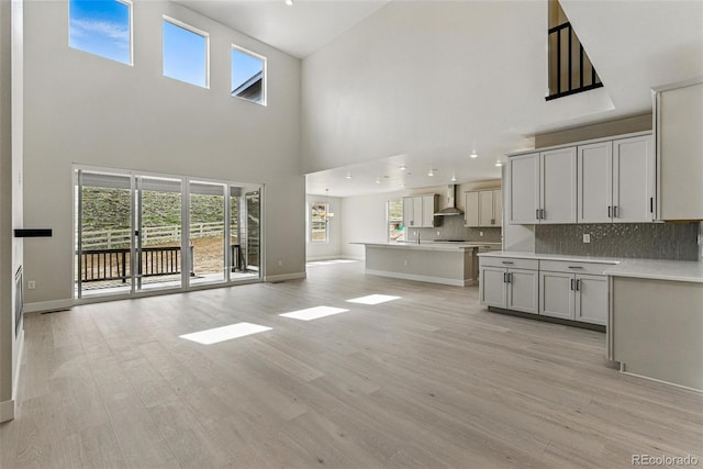 unfurnished living room with a high ceiling, baseboards, a healthy amount of sunlight, and light wood-style floors