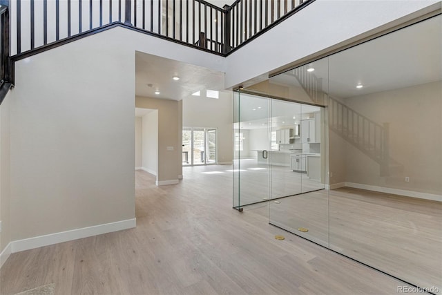 unfurnished living room with baseboards, recessed lighting, a high ceiling, and wood finished floors