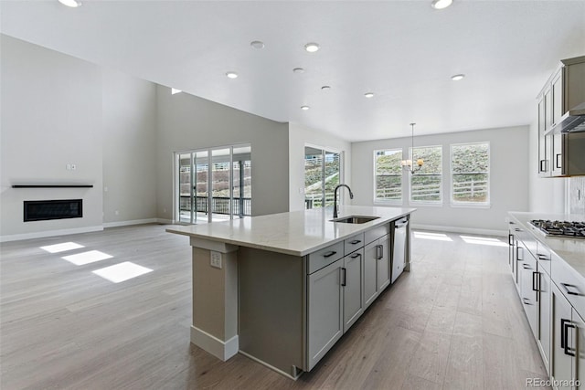kitchen featuring light wood-style floors, baseboards, a glass covered fireplace, and a sink