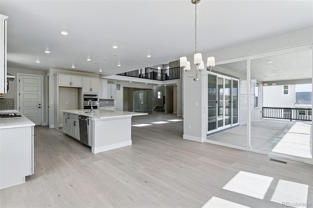 kitchen featuring light countertops, light wood-style floors, open floor plan, and a sink