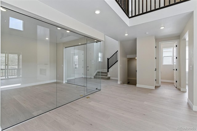 interior space with baseboards, stairway, light wood finished floors, and recessed lighting