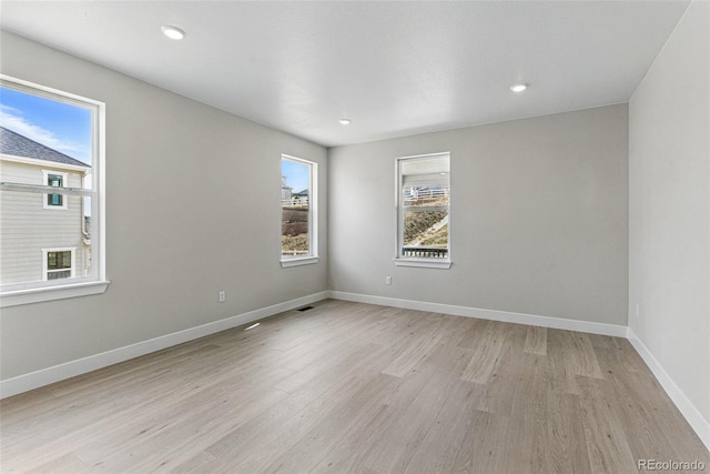 empty room with visible vents, light wood-style flooring, baseboards, and recessed lighting