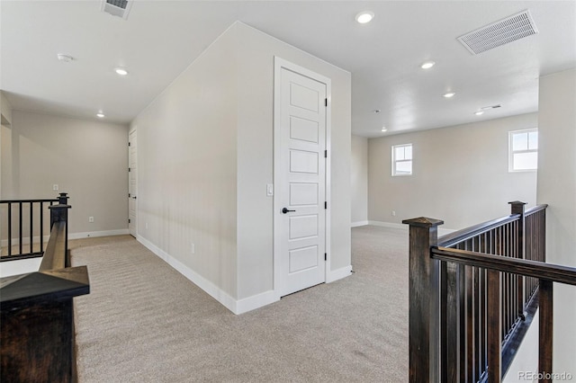 hall featuring an upstairs landing, visible vents, and carpet