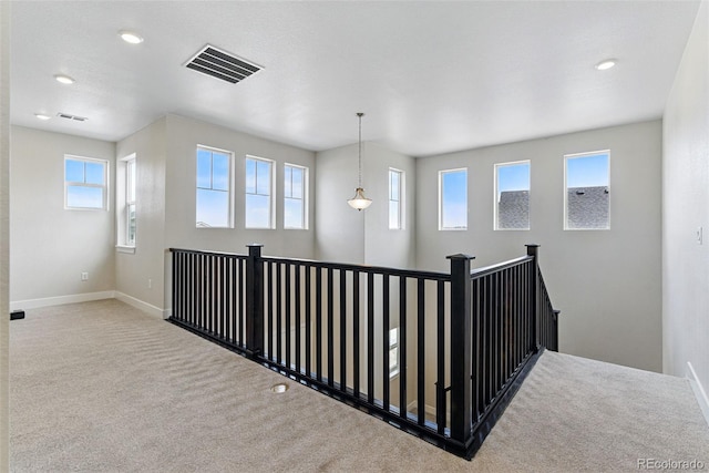 corridor featuring carpet, plenty of natural light, visible vents, and baseboards