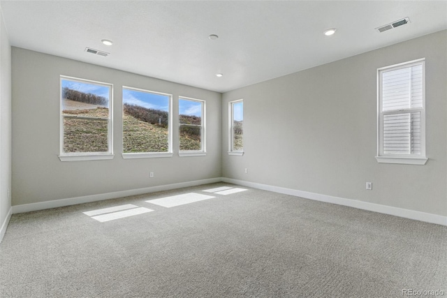 carpeted spare room featuring baseboards, a healthy amount of sunlight, and visible vents