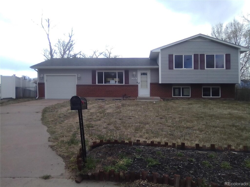 206 Cielo Vista St, Colorado Springs, CO 80911 - split level home featuring driveway, an attached garage, brick siding, and a front yard