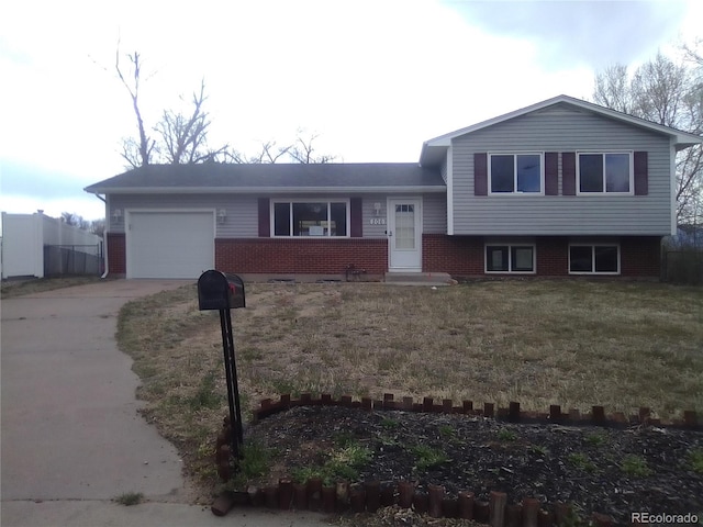 206 Cielo Vista St, Colorado Springs, CO 80911 - split level home featuring driveway, an attached garage, brick siding, and a front yard
