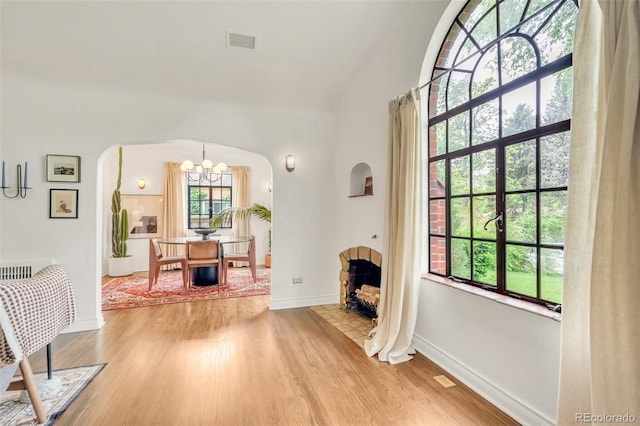1226 Dexter St, Denver, CO 80220 - living area featuring arched walkways, light wood-type flooring, a chandelier, baseboards, and lofted ceiling