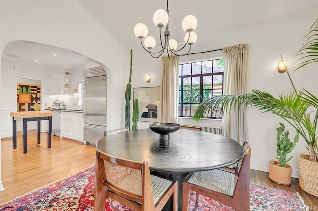 1226 Dexter St, Denver, CO 80220 - dining area with arched walkways, a chandelier, and light wood-style flooring