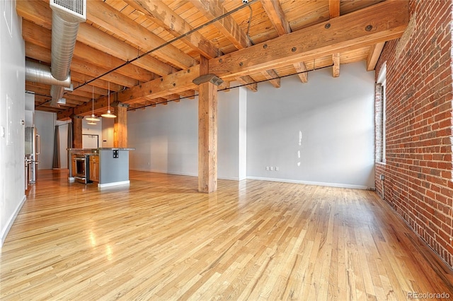 1745 Wazee St Unit 2B, Denver, CO 80202 - unfurnished living room with beam ceiling, light wood-style floors, brick wall, baseboards, and wood ceiling