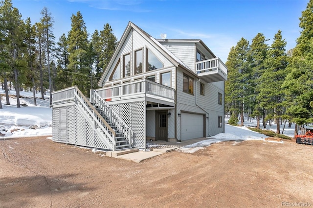 rustic home with a garage, stairway, a balcony, and dirt driveway