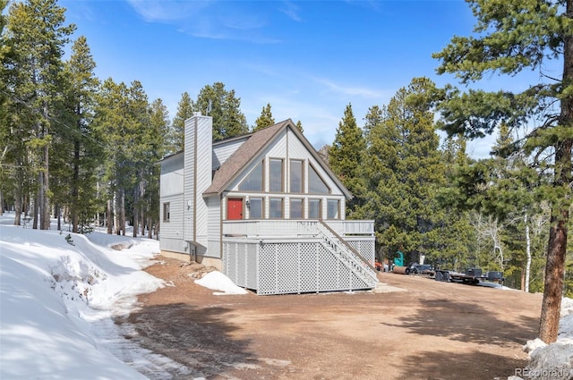 back of property featuring a chimney, a shingled roof, and stairs