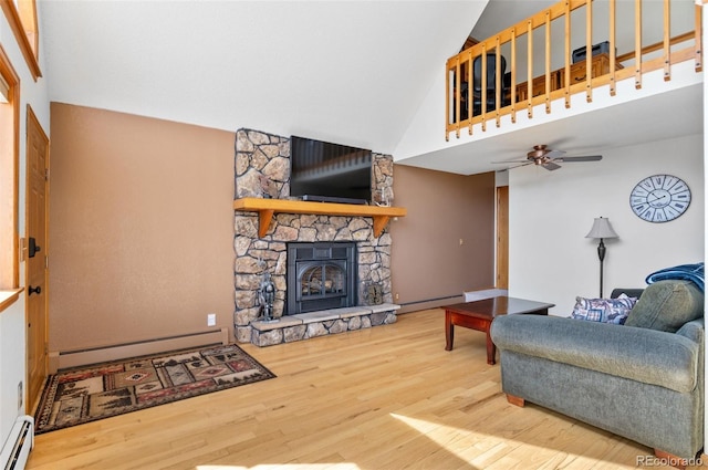 living room with a stone fireplace, a baseboard heating unit, and wood finished floors